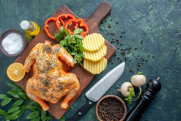 Vista superior de pollo cocido condimentado con patatas en la superficie oscura