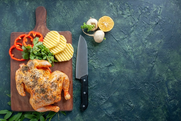 Vista superior de pollo cocido condimentado con patatas en la superficie oscura