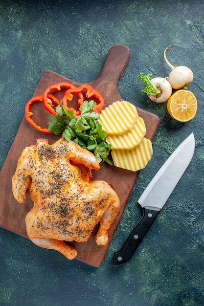 Vista superior de pollo cocido condimentado con patatas en la superficie oscura