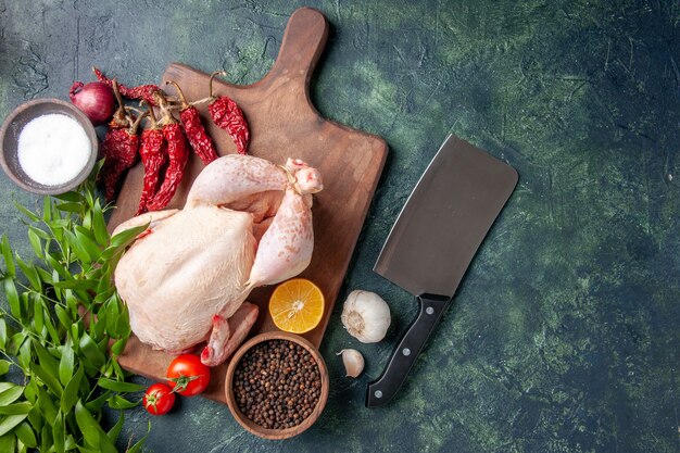 Vista superior pollo crudo fresco con tomates rojos sobre fondo azul oscuro comida de cocina comida de foto de animales granja de carne de pollo