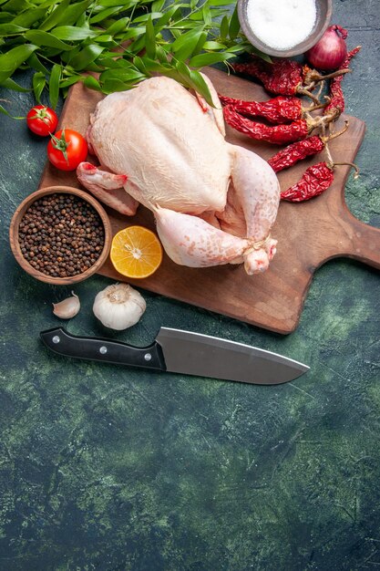 Vista superior de pollo crudo fresco con tomates rojos sobre fondo azul oscuro comida de cocina comida de foto de animales granja de color de pollo