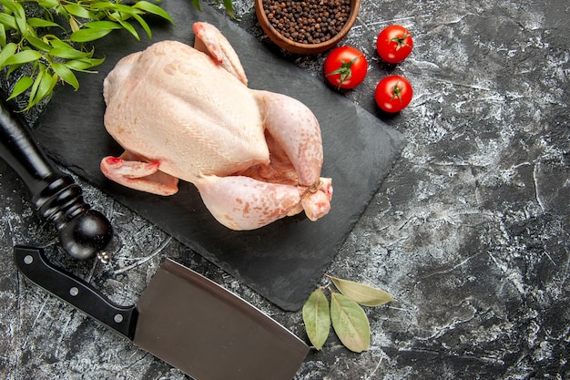 Vista superior pollo crudo fresco con tomates sobre fondo claro-oscuro comida de cocina foto animal carne de pollo granja de color