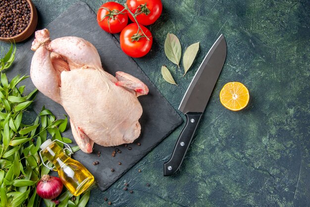 Vista superior pollo crudo fresco con tomates sobre fondo oscuro comida comida para animales pollo cocina color carne