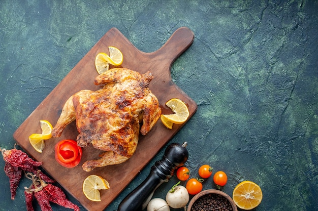 Vista superior de pollo con especias cocidas con rodajas de limón sobre una superficie oscura