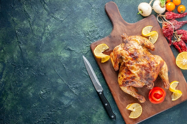 Vista superior de pollo con especias cocidas con rodajas de limón sobre una superficie oscura