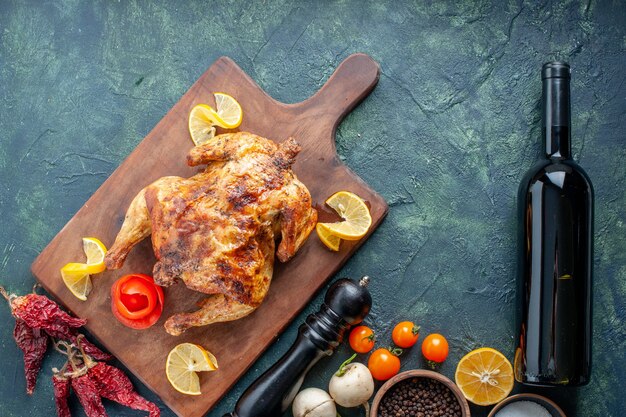 Vista superior de pollo con especias cocidas con rodajas de limón sobre una superficie oscura