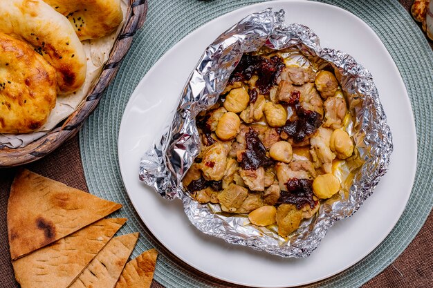 Vista superior de pollo frito en papel de aluminio con frutos secos y castañas y pan