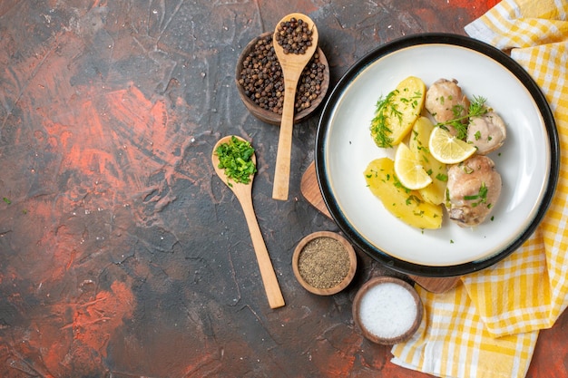 Vista superior de pollo hervido con papas cocidas, verduras y limón sobre un fondo oscuro, salsa, cocina, plato, color, comida, cena, calorías, carne