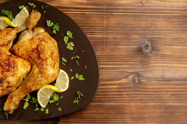 Foto gratuita vista superior de pollo con muslos de pollo al limón con hierbas y limón en el lado izquierdo de la mesa