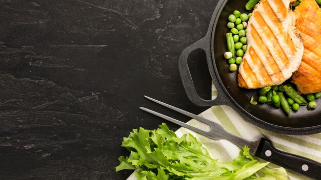 Vista superior de pollo a la parrilla y guisantes en una sartén con espacio de copia