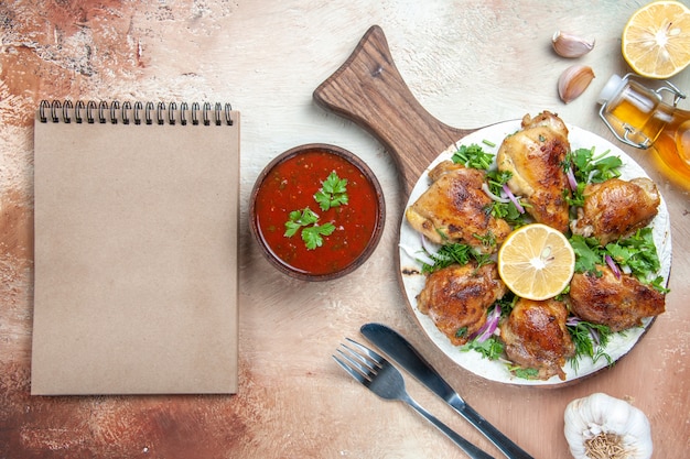 Vista superior de pollo pollo con hierbas de limón en el cuaderno de crema de cuchillo de tenedor de aceite de tablero