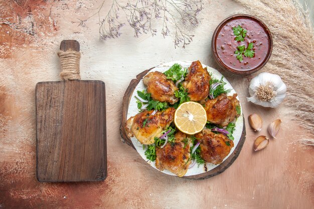 Vista superior pollo pollo con hierbas salsa de limón y ajo junto a la tabla de cortar