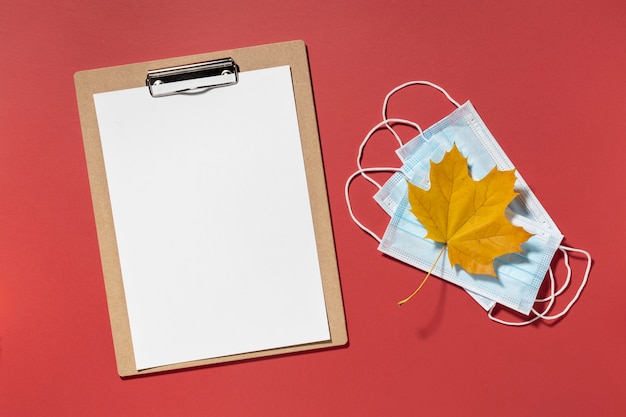 Foto gratuita vista superior del portapapeles con máscaras médicas y hoja de otoño