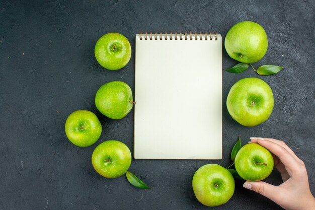 Vista superior portátil manzanas verdes mujer mano sosteniendo manzana sobre superficie oscura