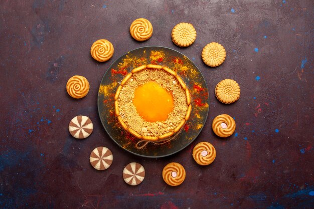Vista superior postre cremoso delicioso pastel amarillo con galletas en la superficie oscura