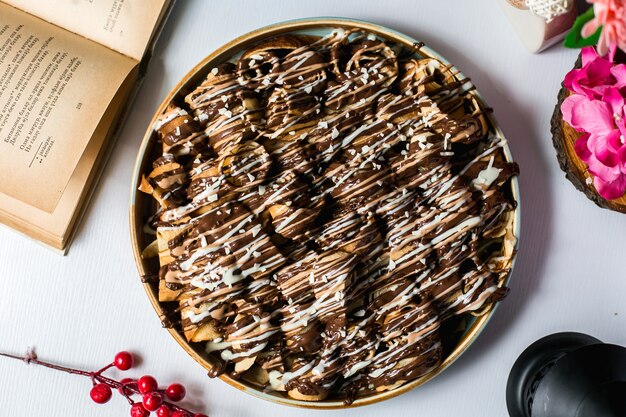 Vista superior de postre con masa rollos cubiertos con jarabe de chocolate sobre la mesa