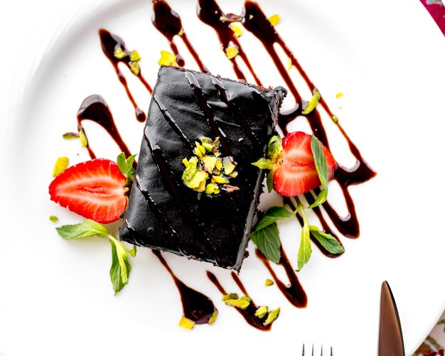 Vista superior postre pastel de chocolate con rodajas de fresa y glaseado de chocolate