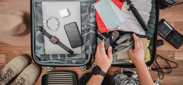 Vista superior de Preparando la maleta para el viaje de vacaciones de verano Joven revisando accesorios y cosas en el equipaje Concepto de vacaciones y vacaciones de viaje