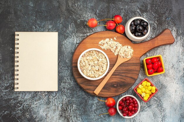 Vista superior de primer plano bayas cuaderno cerezas avena y cuchara en el tablero bayas dulces amarillos