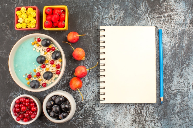 Foto gratuito vista superior de primer plano bayas cuaderno lápiz cereza bayas coloridas avena en los tazones