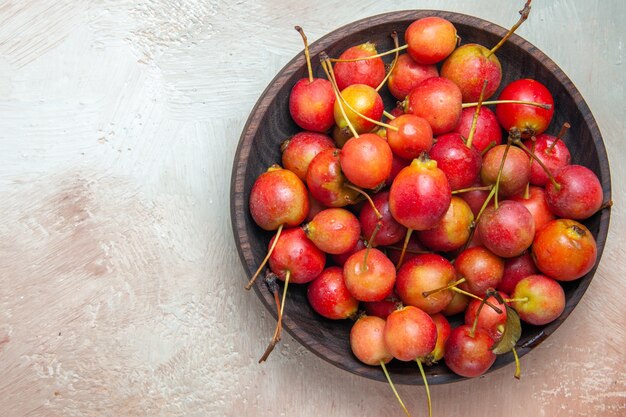 Vista superior de primer plano cerezas las apetitosas cerezas en un tazón marrón sobre la mesa