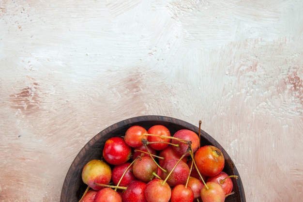 Vista superior de primer plano cerezas tazón de cerezas rojo-amarillo sobre la mesa