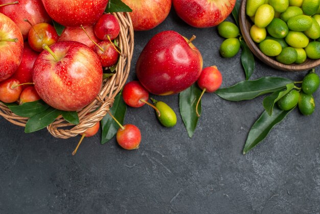 Vista superior de primer plano cítricos mandarinas cerezas manzanas cítricos con hojas en el recipiente