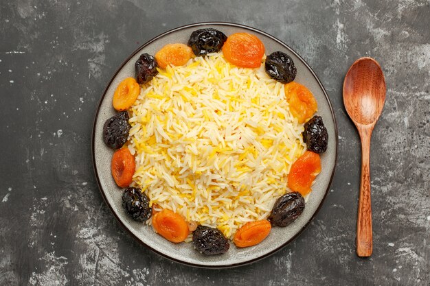 Vista superior de primer plano cuchara de arroz los apetitosos frutos secos y arroz en el plato sobre la mesa