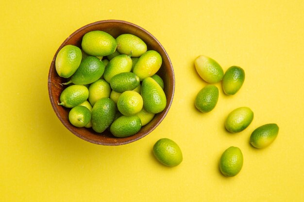 Vista superior de primer plano frutas las apetitosas frutas verdes junto al cuenco en la mesa amarilla