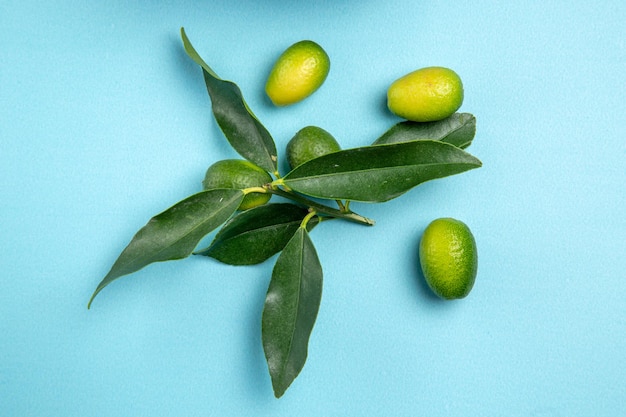 Vista superior de primer plano frutas los apetitosos cítricos con hojas sobre la mesa azul