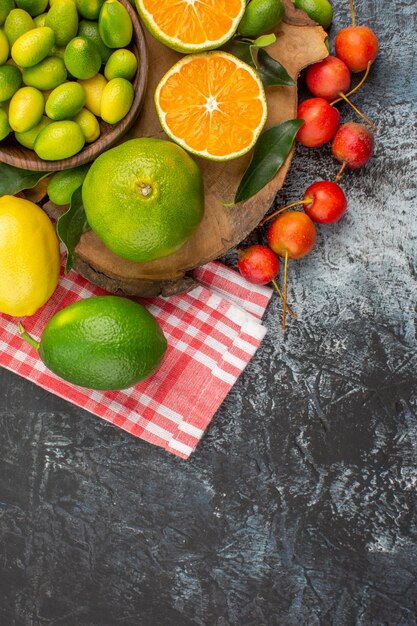 Vista superior de primer plano frutas cítricas manzanas cerezas en el mantel frutas cítricas en el tablero