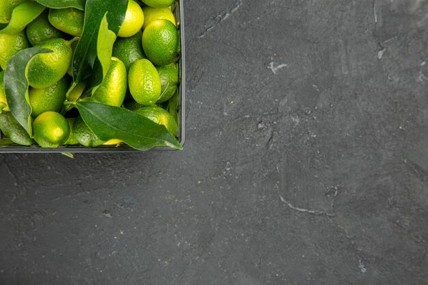 Vista superior de primer plano frutas cítricos con hojas en la canasta sobre la mesa