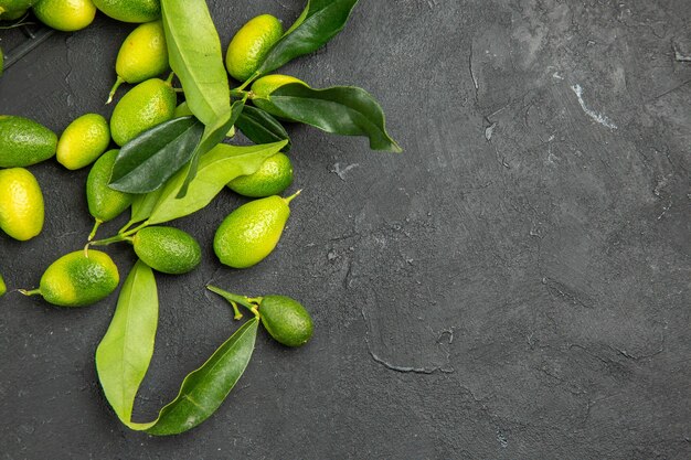 Vista superior de primer plano frutas cítricos con hojas sobre la mesa oscura