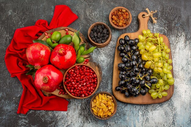 Vista superior de primer plano frutas frutos secos uvas en el tablero granadas sobre el mantel rojo