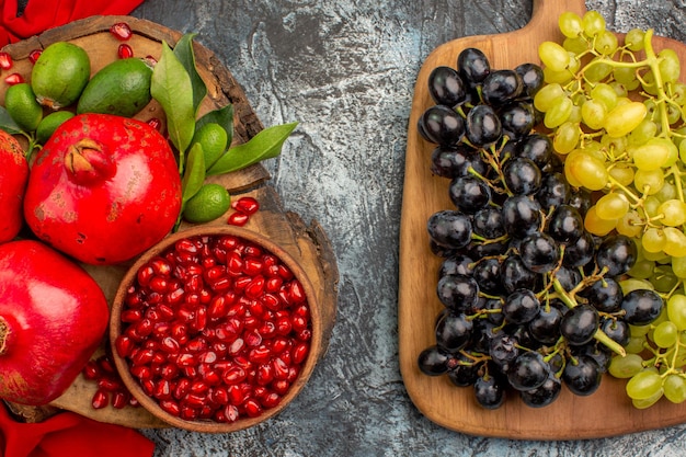 Vista superior de primer plano frutas racimos de uvas en el tablero granadas sobre el mantel rojo