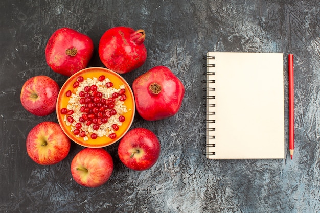 Foto gratuita vista superior de primer plano granadas manzanas granadas avena lápiz cuaderno