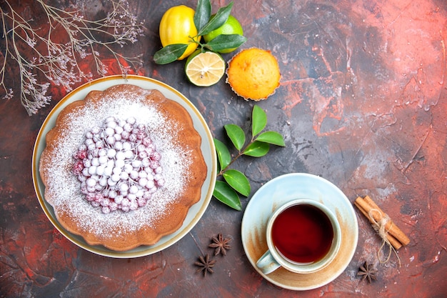 Vista superior de primer plano pastel un pastel con azúcar en polvo cítricos canela anís estrellado una taza de té