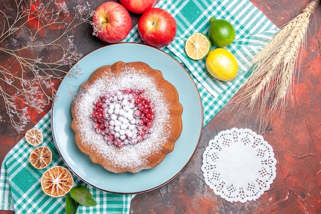 Vista superior de primer plano un pastel un pastel con bayas y tapete de encaje de azúcar frutas cítricas manzanas espigas de trigo