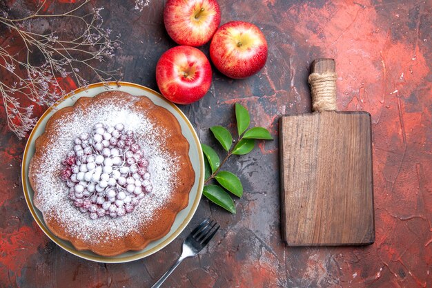 Vista superior de primer plano pastel un pastel con bayas tenedor manzanas deja la tabla de cortar