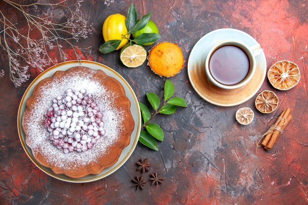 Vista superior de primer plano pastel un pastel una taza de té anís estrellado frutas cítricas cupcake palitos de canela