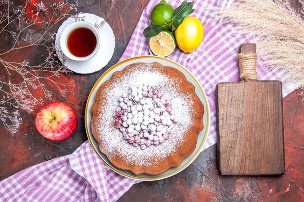 Vista superior de primer plano un pastel un pastel una taza de té frutas cítricas la tabla de cortar espigas de trigo