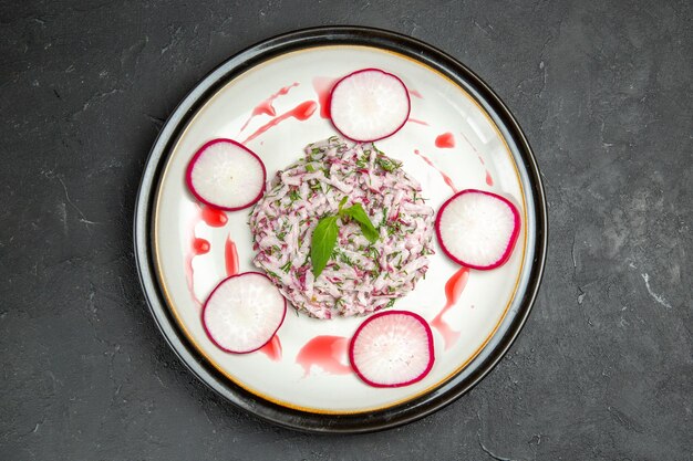 Vista superior de primer plano un plato apetitoso plato de rábano y hierbas con salsa roja