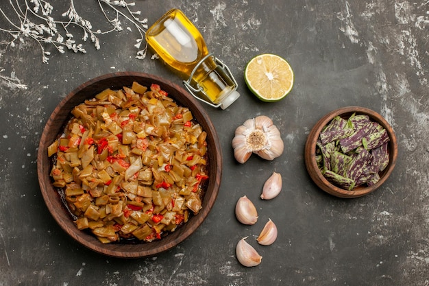 Foto gratuita vista superior de primer plano plato de judías verdes plato de judías verdes y tomates junto a la botella de aceite de ajo y limón sobre la mesa