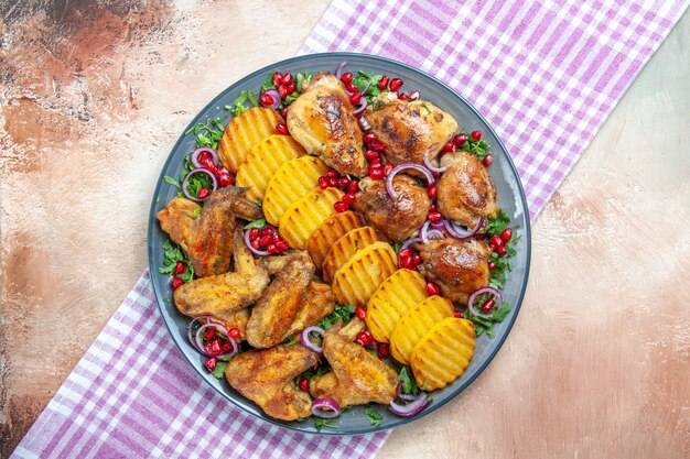 Vista superior de primer plano plato de pollo de pollo patatas hierbas cebolla sobre el mantel a cuadros