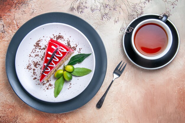 Vista superior de primer plano un plato de tarta de tarta con salsas de chocolate cítricos tenedor una taza de té