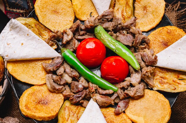 Vista superior de primer plano un plato tradicional azerbaiyano salvia de carne con pan de pita patatas tomates y pimiento verde