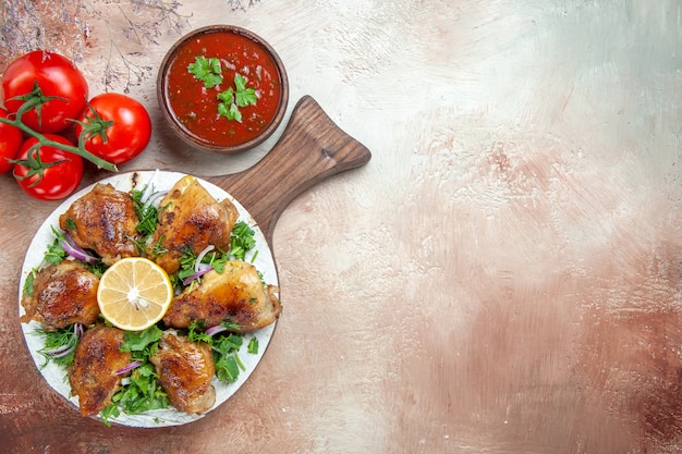 Vista superior de primer plano pollo pollo con hierbas de limón en el tablero salsa tomates con pedicelos