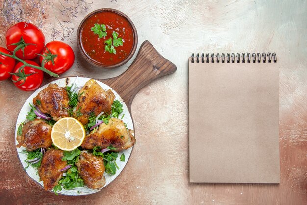 Vista superior de primer plano salsa de pollo tomates pollo con hierbas de limón en el cuaderno de crema de tablero