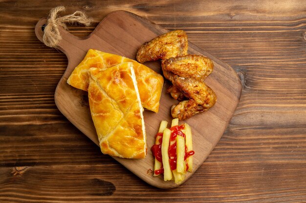 Vista superior de primer plano tartas y pollo apetitoso pastel de alitas de pollo y patatas fritas con salsa de tomate