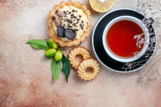 Vista superior de primer plano una taza de té cupcake cookies una taza de té frutas cítricas